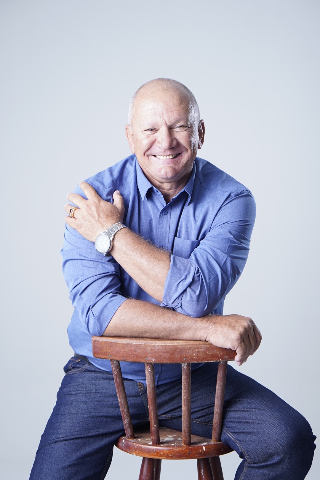 Gilberto Rezende sorrindo, apoiado em uma cadeira