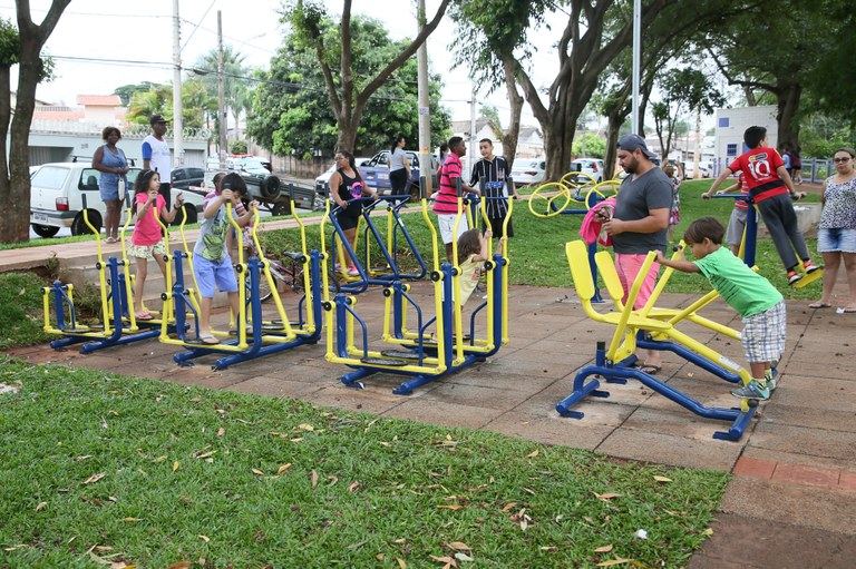 Academia ao ar livre do parque com famílias e crianças usando os aparelhos
